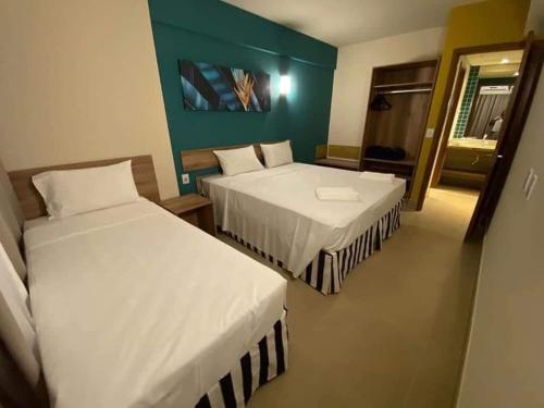 una camera da letto con due letti e una parete verde di Hotel Resort Próximo ao Parque Thermas a Olímpia