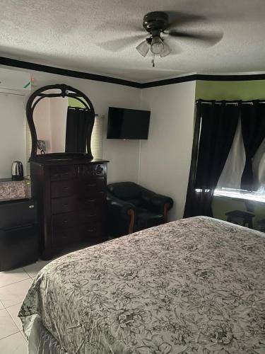 una camera con letto, cassettiera e ventilatore di Hide Away From Home a May Pen