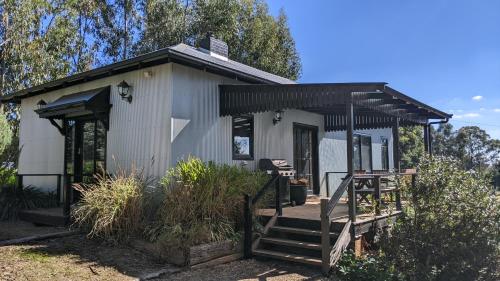 a small white house with a porch and stairs at Whispering Moon Cottage in Orange