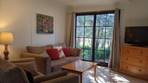 a living room with a couch and a tv at Whispering Moon Cottage in Orange