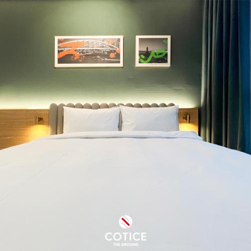 a bedroom with a white bed with two pictures on the wall at Cotice The Bridge in Busan