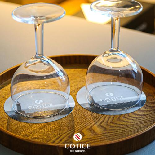 two wine glasses sitting on top of a wooden tray at Cotice The Bridge in Busan