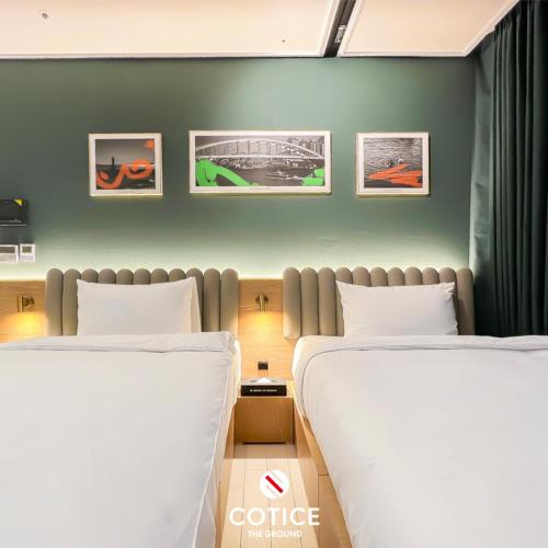 two beds in a room with pictures on the wall at Cotice The Bridge in Busan
