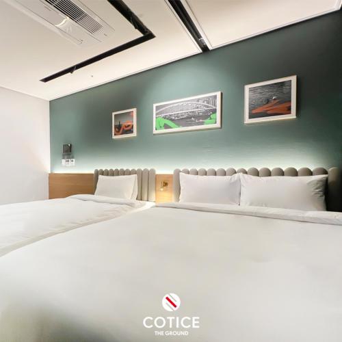 a white bed in a room with a green wall at Cotice The Bridge in Busan