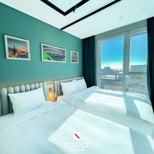 a hotel room with two beds and a large window at Cotice The Bridge in Busan