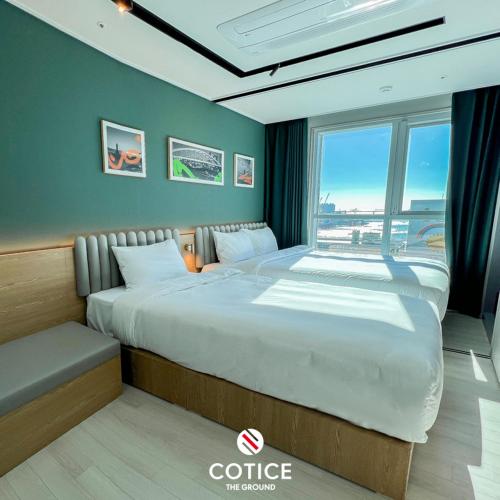 two beds in a room with a large window at Cotice The Bridge in Busan