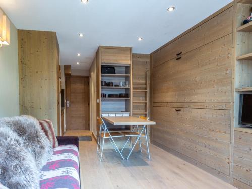 Cette chambre dispose d'une table et d'un mur en bois. dans l'établissement Studio chaleureux et élégant, front de neige à Val d'Isère, proche centre et pistes - FR-1-694-190, à Val dʼIsère