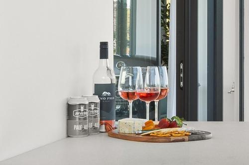 a bottle of wine and two glasses of wine and cheese at Allura Escapes by Experience Jervis Bay in Huskisson