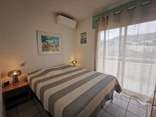 une chambre avec un lit et une fenêtre dans l'établissement T2 Cabine 4 pers, pieds dans l'eau avec wifi, parking et clim - FR-1-803-1, au Lavandou