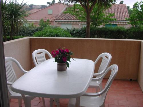 une table et des chaises blanches avec une plante en pot dans l'établissement Appartement 2 pièces confortable au Lavandou 34m² + terrasse, à 800m de la plage, 4 personnes. - FR-1-803-17, au Lavandou