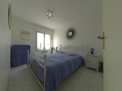 - une chambre avec un lit doté d'un couvre-lit bleu et d'un miroir dans l'établissement Appartement 2 pièces confortable au Lavandou 34m² + terrasse, à 800m de la plage, 4 personnes. - FR-1-803-17, au Lavandou