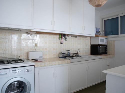 une cuisine avec des armoires blanches et une machine à laver dans l'établissement Le Lavandou, T2 climatisé pour 4 pers avec parking près de la plage - FR-1-803-28, au Lavandou