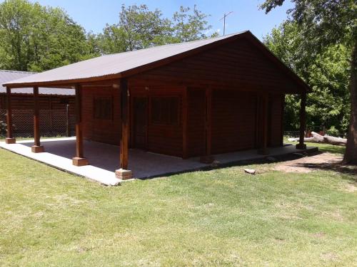 a wooden building with a roof on the grass at Cabaña NANO in Tanti