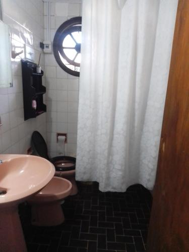 a bathroom with a toilet and a white shower curtain at Alojamiento Pichinchas in Paso de los Libres