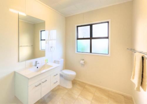 a bathroom with a sink and a toilet and a window at Bucks Point - Norfolk Island Holiday Homes in Burnt Pine