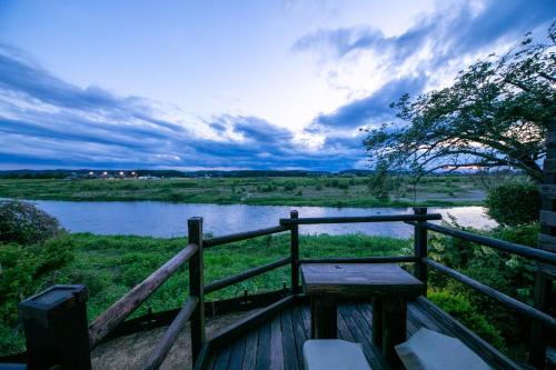 a wooden bench next to a river with a fence at Isamikan in Nakagawa