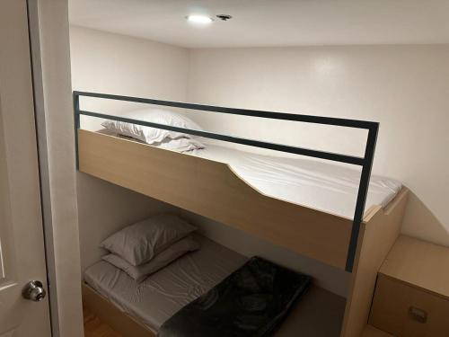 マニラにあるCylo's Place Spacious 2BR Apt linked to MRT Station near GMA 7の白いシーツの二段ベッドのある寝室