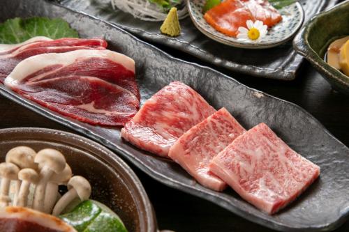a table topped with three trays of meat and vegetables at Isamikan in Nakagawa