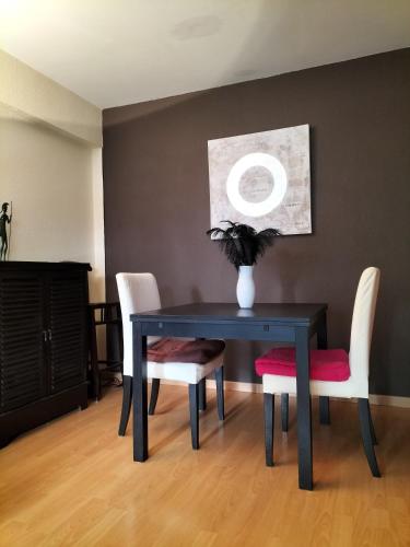 une table de salle à manger noire avec des chaises blanches et un vase dans l'établissement Rémy Dumoncel, à Paris