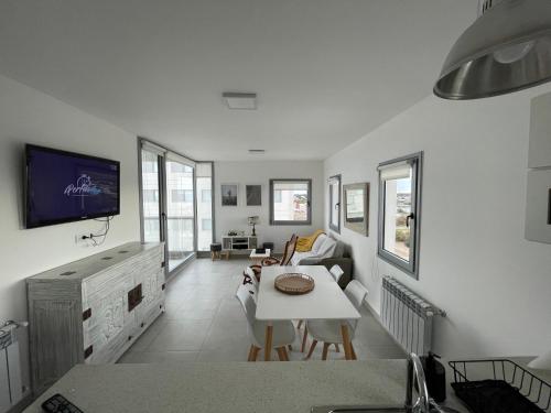 Una sala de estar blanca con una mesa y un televisor. en Torres al Mar, en Monte Hermoso