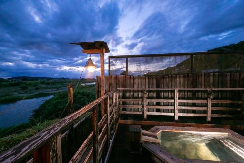 a wooden building with a hot tub next to a river at Isamikan in Nakagawa