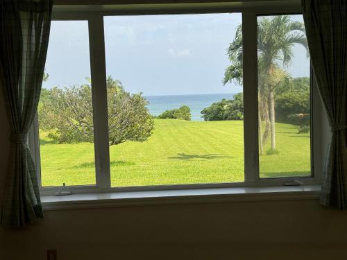 a window with a view of a field of grass at Beachfront Paradise Ishigaki in Ishigaki Island