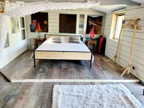 une chambre avec un lit et un parquet dans l'établissement La cabane atypique, à Gujan-Mestras