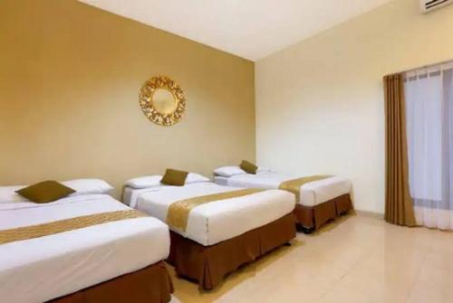 3 Betten in einem Zimmer mit einem Wandspiegel in der Unterkunft The Bali Rama City Hotel in Denpasar