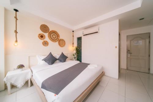a white bedroom with a bed and a table at Catnip Seaside Hotel&Cafe in Ban Huai Luk (1)