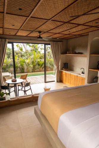 a bedroom with a bed and a table and a kitchen at SIVANA, Hotel Boutique with ocean or garden views - Adults only in Uluwatu
