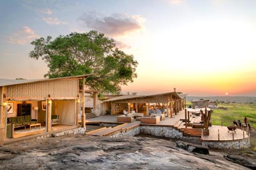 an image of a house with the sunset in the background at One Nature Mara River in Serengeti National Park