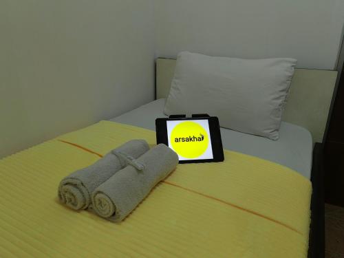 a bed with two towels and a tablet with a sign on it at Cibubur Village By Arsakha Property Management in Cibubur