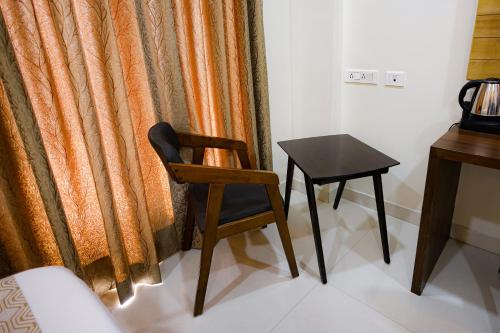 a chair and a table in front of a curtain at M Square Hotel in Hyderabad