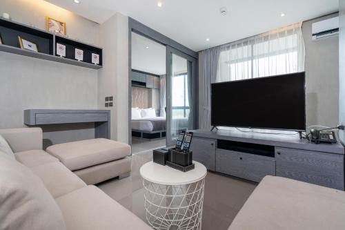 a living room with a flat screen tv and a couch at Tropics Pool View 2BR Kamala Apartment CTG P605-6, near Beach in Kamala Beach