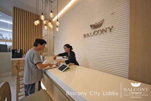 two people standing at a counter in a store at Balcony Courtyard Sriracha Hotel & Serviced Apartments in Si Racha