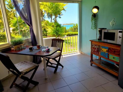 een eetkamer met een tafel en stoelen en een raam bij ILET BLEU studio cosy RDC vue mer et jardin - Accès direct plage in Le Gosier