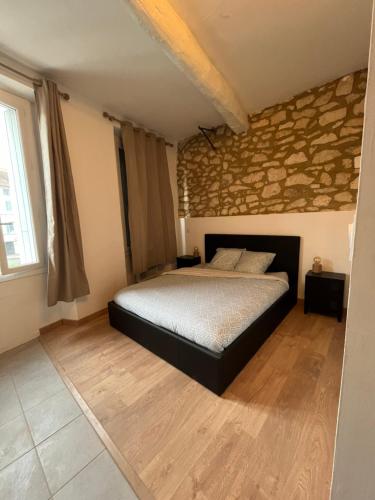 une chambre avec un lit et un mur en pierre dans l'établissement Studio Carpentras, à Carpentras