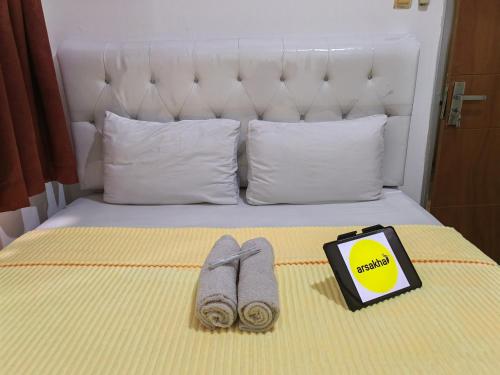 a bed with two slippers and a book on it at Mailbox Arsakha Lobi B Cibubur Village in Cibubur