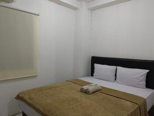 a bed with a towel laying on top of it at Mailbox Arsakha Lobi B Cibubur Village in Cibubur