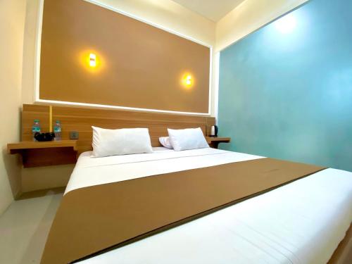 a bedroom with a large white bed with two pillows at Al-Kiswah Syariah Guest House in Blitar