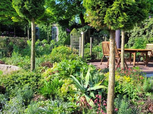 a garden with a table and benches and flowers at Villa in Overloon near War Museum in Overloon