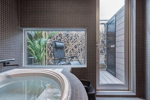 a bathroom with a mirror and a tub with a chair at eni suite tennoji in Osaka