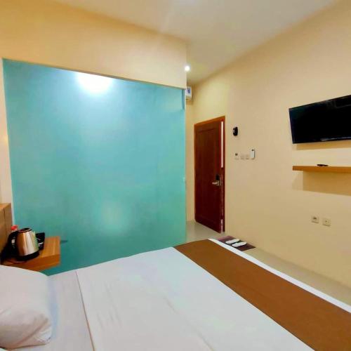a bedroom with a large bed and a flat screen tv at Al-Kiswah Syariah Guest House in Blitar