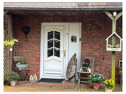 a white door of a brick house with flowers at LUV and LEE Comfortable holiday residence in Wesselburenerkoog