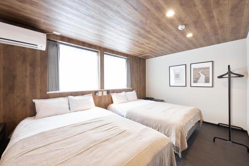 two beds in a room with wooden walls and windows at eni suite tennoji in Osaka