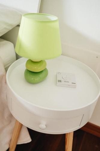 a green lamp on a white table next to a bed at Galé Suite Apartment in Chieti