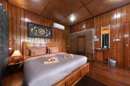 a bedroom with a large bed with wooden walls at Kanecha's Home Lampang in Lampang