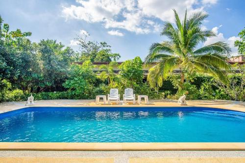 a swimming pool with two chairs and a palm tree at Samran Resort in Chalong