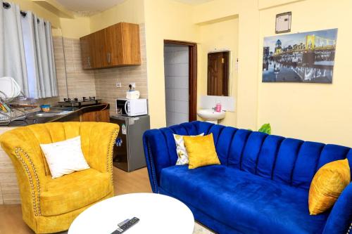 a living room with a blue couch and two chairs at Studio Apartment, Kisii in Kisii