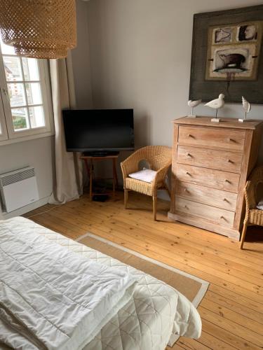 a bedroom with a bed and a dresser and a television at La Musardiere in La Baule